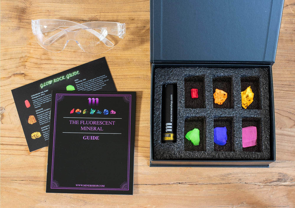 fluorescent mineral kit containing a UV flashlight, ruby, fluorescent sodalite, wernerite, opal, fluorite, calcite rhomb