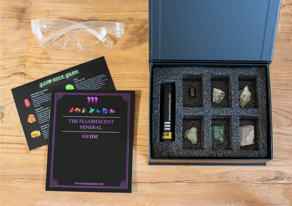 fluorescent mineral kit containing a UV flashlight, ruby, fluorescent sodalite, wernerite, opal, fluorite, calcite rhomb